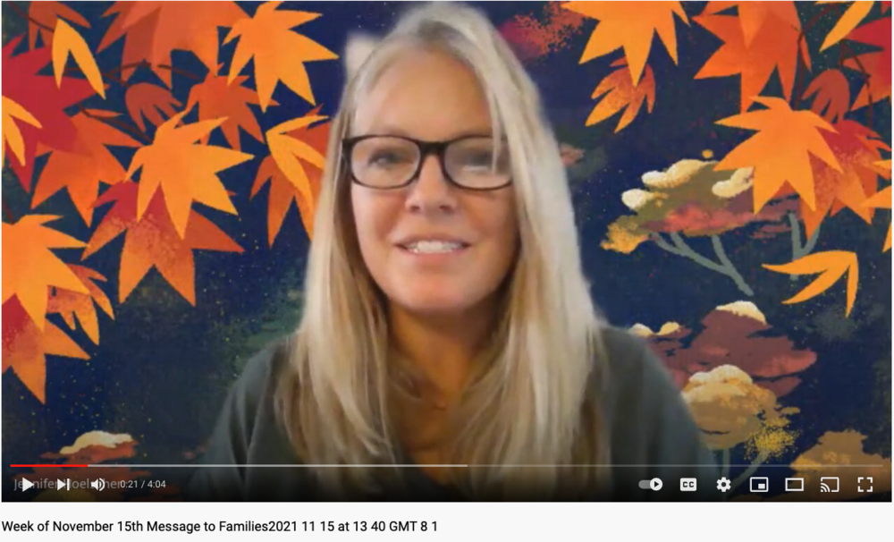 woman with blond hair and glasses in front of backdrop with multi-colored leaves